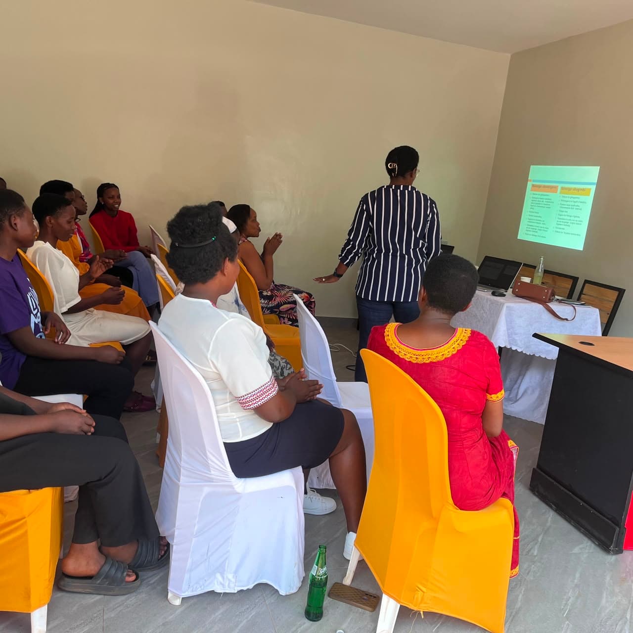 A trainer presents to seated participants during a WHOFD caregiver training session